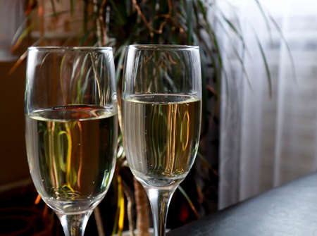 Beautiful two glasses of champagne standing on the table against the background of a blurred room in the interior. Soft focus. Shallow depth of fieldの写真素材