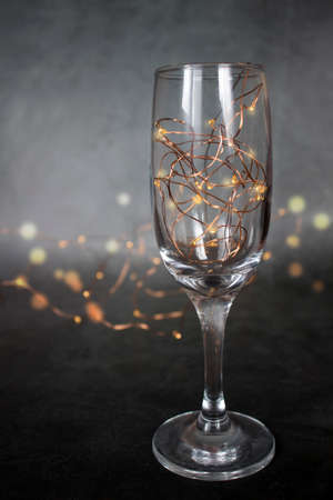 New Year decorations in the form of garland lights in a champagne glass and in the background. selective focus. Blur. festive minimalist composition. the concept of Christmas and New Year. A place for text. A copyspace. verticalの写真素材