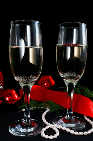 Two glasses of champagne on the festive table on a dark background. next to Christmas decor red balls, ribbon, beads. Christmas composition. Selective focusの写真素材