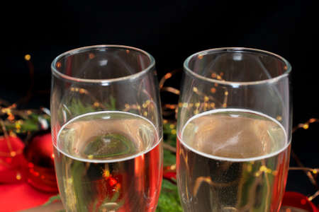 Two glasses with a festive drink of sparkling champagne close-up. Selective focus. In the background bright lights and New Year's decoration. The concept of Christmas, good mood, holiday.の写真素材