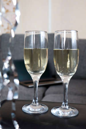 Two glasses of champagne in an office setting. New Year's decorations, selective focus. Laptop in the background. the concept of celebrating the New Year and Christmas holidays in the office at work. celebrate corporate success and new year eventの写真素材