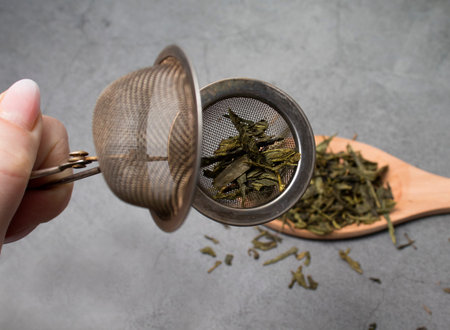 hand holds a strainer with green tea close-up