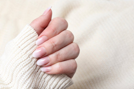 Women's hands with a beautiful delicate white manicure close-up. Female nail manicure. Luxurious design of nails on the beautiful hands of a womanの写真素材