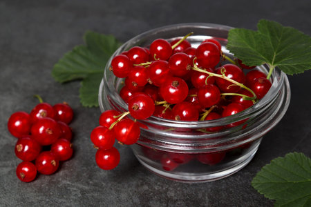 Red currants leaves in a glass plate on a black cement background. The concept of a summer harvest...