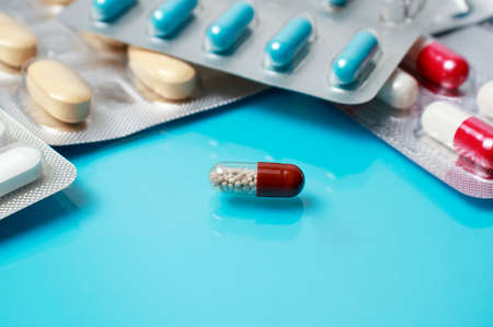 Pills, tablets or capsules on light blue medical reflective background. Medicine, health, treatment, pharmacy concept. Medical background.の写真素材