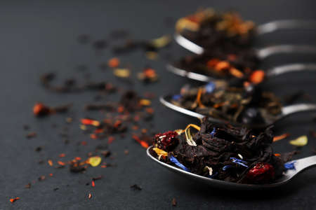 Dried Tea Leaves in a teaspoon. Assortment of bright tea on a dark table, composition with different types of tea. The concept of tea. copy spase.の写真素材