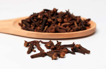 dried cloves in a wooden spoon, on a white background. spicy herb for food flavor and natural medicine.の写真素材