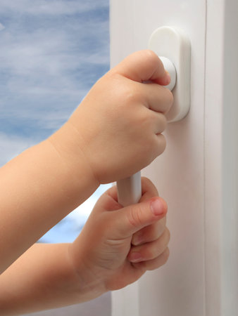 The child's hands are holding the plastic window handle. The concept of children falling out of...