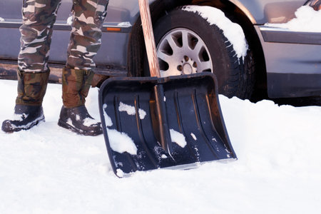 Shovel snow removal. Cleaning the car from snow in winter. Snow-covered car after a snowfall....