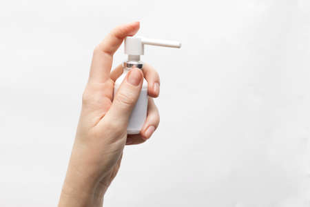 Throat spray medicine in hand on white background. Medical, health treatment concept. Medicine bottle to spray injections into the mouth. To treat mouth sore or sore throat, copy space.の写真素材