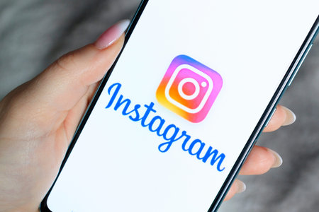 The Instagram logo on the smartphone screen is in womens hands. The concept of using social...