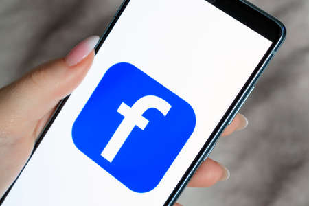 Woman holds smart phone with facebook application on the screen. facebook is a photo-sharing app for smartphones. March 13, 2022 - Mogilev. Belarusのeditorial素材