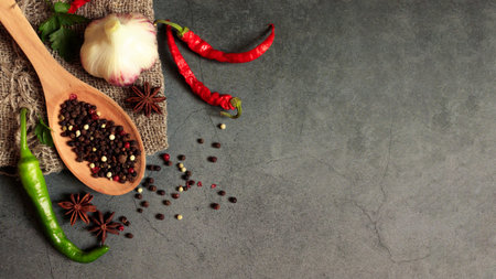 A set of spices on a dark background with a place for text. Assortment of peppers in a wooden spoon,...