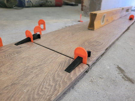 Laying tiles at home. Leveling floor tiles with a level.