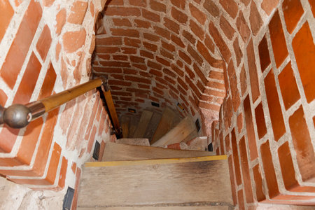 A wooden staircase leading to the bottom among the red brick wallsの写真素材