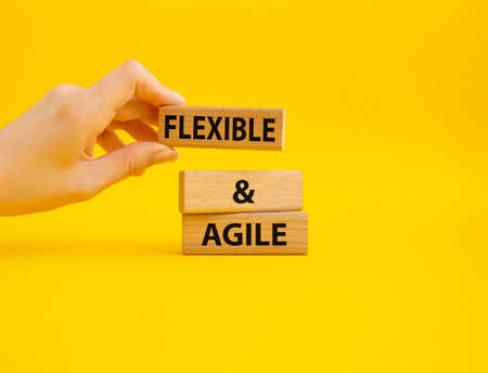 Flexible and agile symbol. Concept word Flexible and agile on wooden blocks. Beautiful yellow background. Businessman hand. Business and Flexible and agile concept. Copy spaceの写真素材