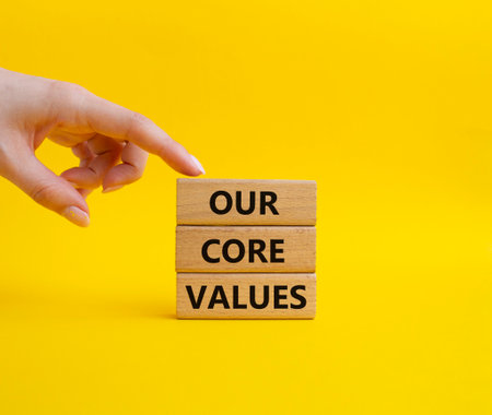 Our core values symbol. Concept words 'Our core values' on wooden blocks. Beautiful yellow background. Businessman hand. Business and Our core values concept. Copy space.の写真素材