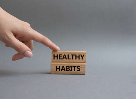 Healthy habits symbol. Concept word Healthy habits on wooden blocks. Beautiful grey background. Businessman hand. Business and Healthy habits concept. Copy spaceの写真素材
