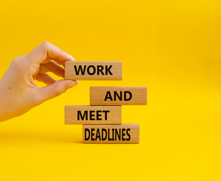 Work and deadline symbol. Concept words Work and meet deadlines on wooden blocks. Beautiful yellow background. Business and Work and meet deadlines concept. Copy space.の写真素材