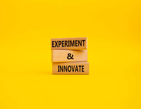 Experiment and innovate symbol. Concept words Experiment and innovate on wooden blocks. Beautiful yellow background. Business and Experiment and innovate concept. Copy space.の写真素材