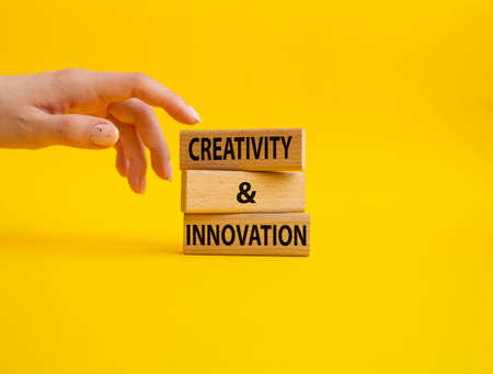Creativity and innovation symbol. Concept word Creativity and innovation on wooden blocks. Beautiful yellow background. Businessman Hand. Business and Creativity and innovation concept. Copy spaceの写真素材
