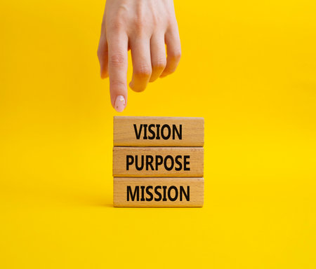 Vision Purpose Mission symbol. Concept word Vision Purpose Mission on wooden blocks. Beautiful yellow background. Businessman hand. Business and Vision Purpose Mission concept. Copy space.の写真素材