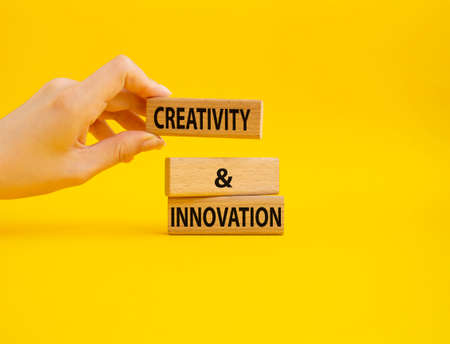 Creativity and innovation symbol. Concept word Creativity and innovation on wooden blocks. Beautiful yellow background. Businessman Hand. Business and Creativity and innovation concept. Copy spaceの写真素材