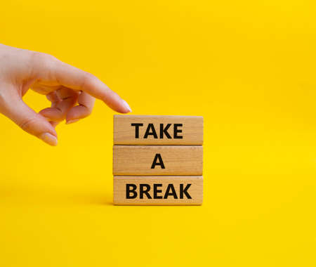 Take a break symbol. Concept words 'Take a break' on wooden blocks. Beautiful yellow background. Businessman hand. Business and Take a break concept. Copy space.の写真素材
