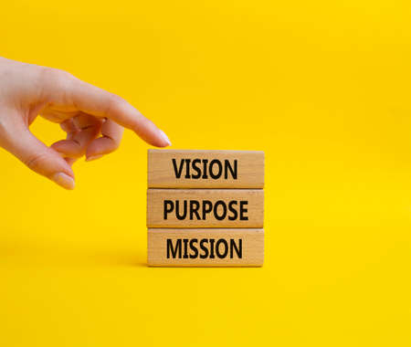 Vision Purpose Mission symbol. Concept word Vision Purpose Mission on wooden blocks. Beautiful yellow background. Businessman hand. Business and Vision Purpose Mission concept. Copy space.の写真素材