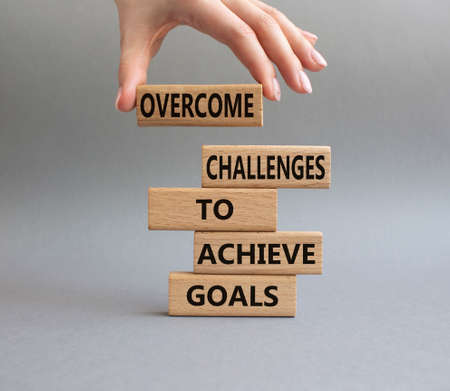 Challenges or goals symbol. Wooden blocks with words 'Overcome challenges to achieve goals'. Beautiful grey background. Business and 'Overcome challenges to achieve goals' concept. Copy space.の写真素材