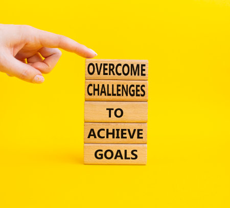Challenges or goals symbol. Wooden blocks with words 'Overcome challenges to achieve goals'. Beautiful yellow background. Business and 'Overcome challenges to achieve goals' concept. Copy space.の写真素材