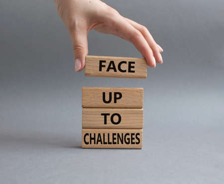 Face up to challenges symbol. Wooden blocks with words Face up to challenges. Beautiful grey background. Businessman hand. Business and Face up to challenges concept. Copy space.の写真素材