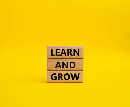 Learn and grow symbol. Concept words 'Learn and grow' on wooden blocks. Beautiful yellow background. Business and Learn and grow concept. Copy space.の写真素材