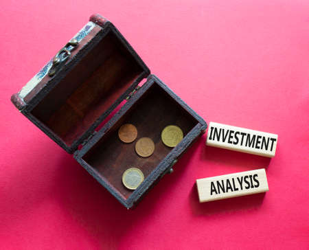 investment analysis symbol. Wooden blocks with words 'investment analysis' with wooden box. Beautiful red background. Business and 'investment analysis' concept. Copy space.の写真素材