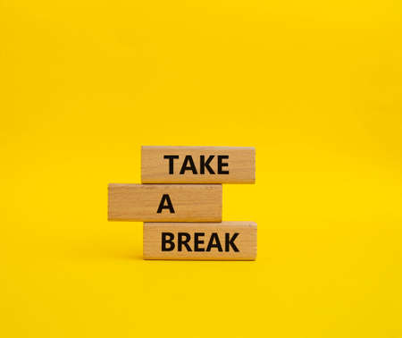 Take a break symbol. Concept words 'Take a break' on wooden blocks. Beautiful yellow background. Business and Take a break concept. Copy space.の写真素材
