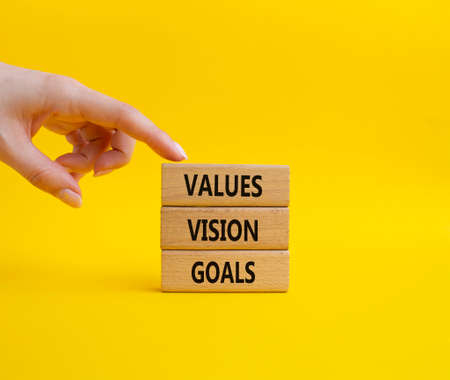 Values Vision Goals symbol. Concept words Values Vision Goals on wooden blocks. Beautiful yellow background. Busimessman hand. Business and Values Vision Goals concept. Copy space.の写真素材