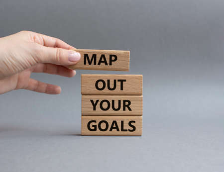 Goals symbol. Wooden blocks with words Map out your goals. Beautiful grey background. Businessman hand. Business and 'Map out your goals' concept. Copy space.の写真素材