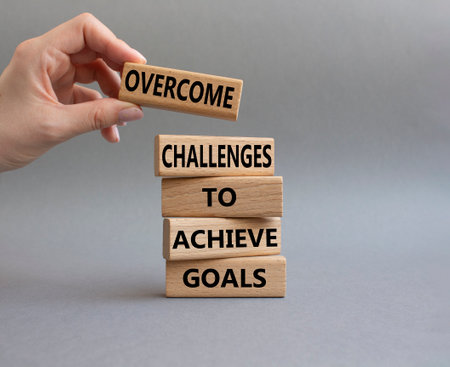 Challenges or goals symbol. Wooden blocks with words 'Overcome challenges to achieve goals'. Beautiful grey background. Business and 'Overcome challenges to achieve goals' concept. Copy space.の写真素材