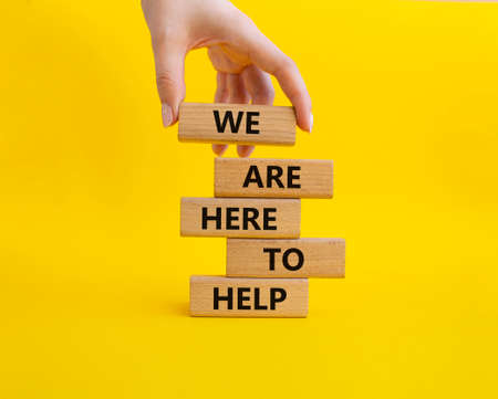 We are here to help symbol. Concept words we are here to help on wooden blocks. Beautiful yellow background. Business and we are here to help concept. Copy space.の写真素材