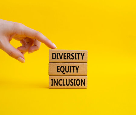Diversity Equity Inclusion symbol. Concept words Diversity Equity Inclusion on wooden blocks. Beautiful yellow background. Bisinessman hand. Business and Diversity Equity Inclusion concept. Copy space.の写真素材