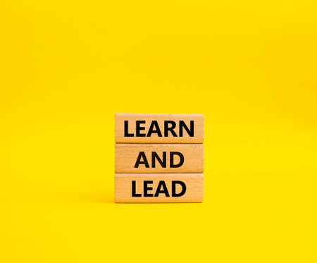 Learn and lead symbol. Concept words 'Learn and lead' on wooden blocks. Beautiful yellow background. Business and Learn and lead concept. Copy space.の写真素材