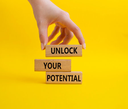 Unlock your Potential symbol. Wooden blocks with words Unlock your Potential. Beautiful yellow background. Businessman hand. Business and Unlock your Potential concept. Copy space.の写真素材