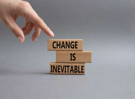Change is Inevitable symbol. Wooden blocks with words Change is Inevitable. Beautiful grey background. Businessman hand. Business and Change is Inevitable concept. Copy space.の写真素材