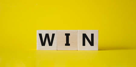 Win symbol. Wooden blocks with words Win. Beautiful yellow background. Business and Win concept. Copy space.の写真素材