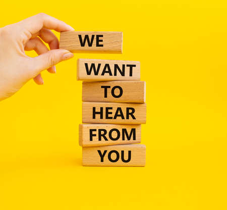 We want to hear from you symbol. Wooden blocks with words We want to hear from you. Beautiful yellow background. Businessman hand. Business and We want to hear from you. Copy space.の写真素材