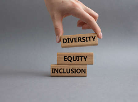 Diversity Equity Inclusion symbol. Concept words Diversity Equity Inclusion on wooden blocks. Beautiful grey background. Business and Diversity Equity Inclusion concept. Businessman hand. Copy space.の写真素材