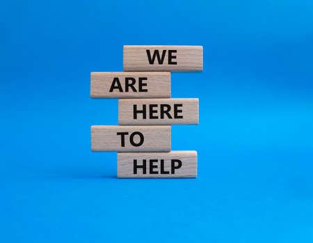 We are here to help symbol. Concept words we are here to help on wooden blocks. Beautiful blue background. Business and we are here to help concept. Copy space.の写真素材