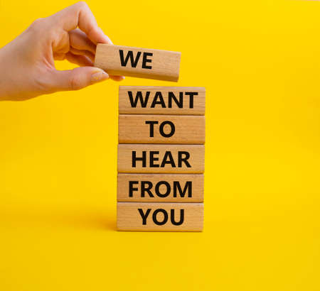 We want to hear from you symbol. Wooden blocks with words We want to hear from you. Beautiful yellow background. Businessman hand. Business and We want to hear from you. Copy space.の写真素材