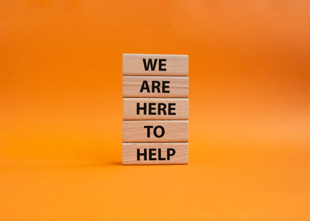 We are here to help symbol. Concept words we are here to help on wooden blocks. Beautiful orange...