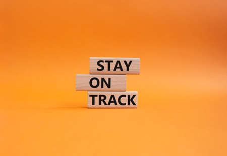 Stay on track symbol. Wooden blocks with words 'Stay on track'. Beautiful orange background. Business and 'Stay on track' concept. Copy space.の写真素材